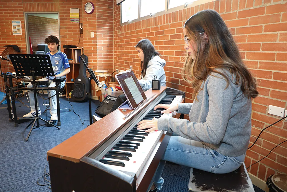 Estudiante toca el piano durante una actividad musical del Gimnasio La Montaña
